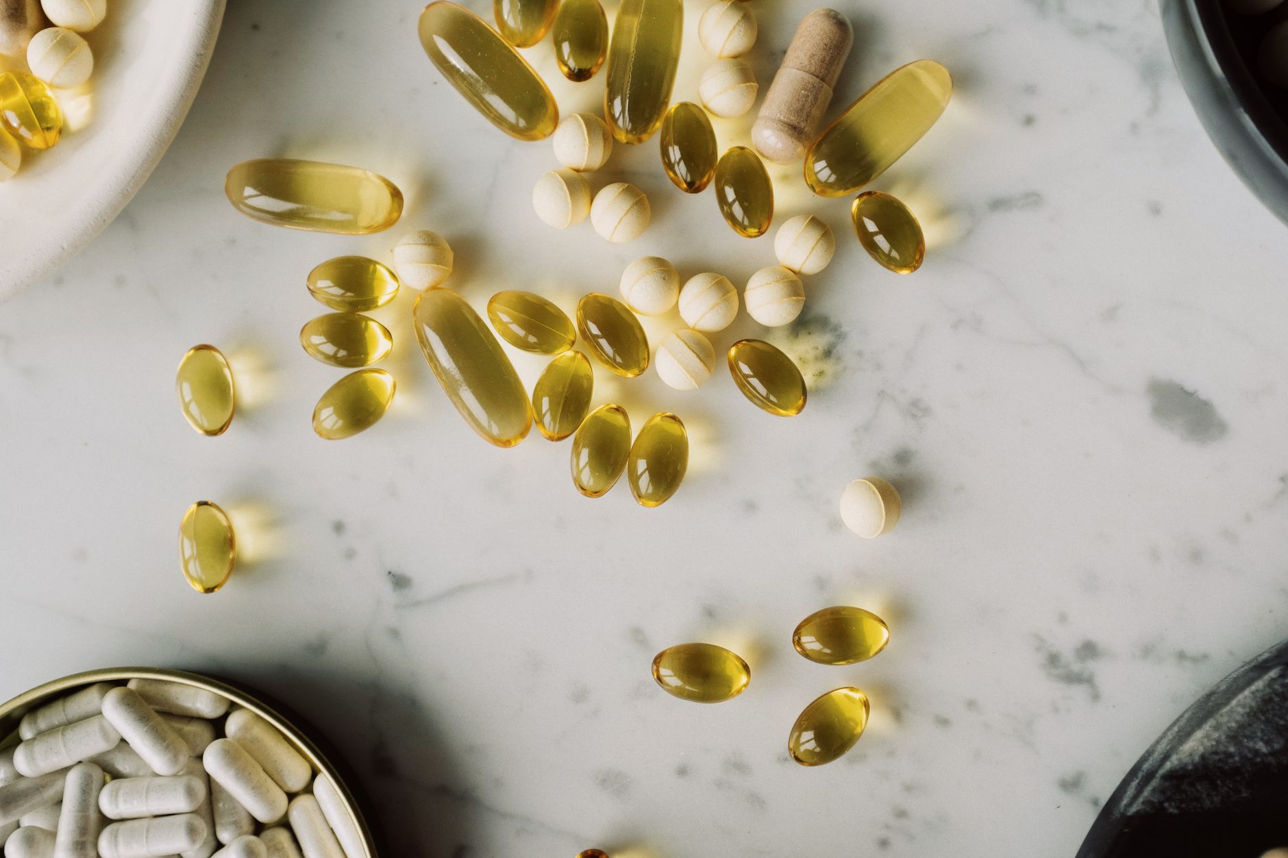 Gélules et capsules jaunes éparpillées sur un plan en marbre