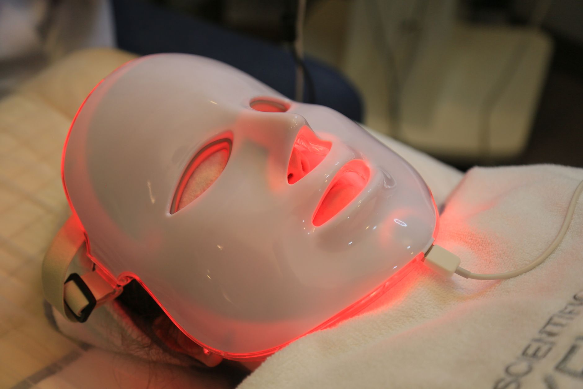 Masque LED allumé en lumière rouge sur le visage d’une femme allongée