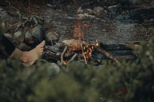 Un paysage extérieur paisible avec un petit feu de camp et un pied nu qui se réchauffe.