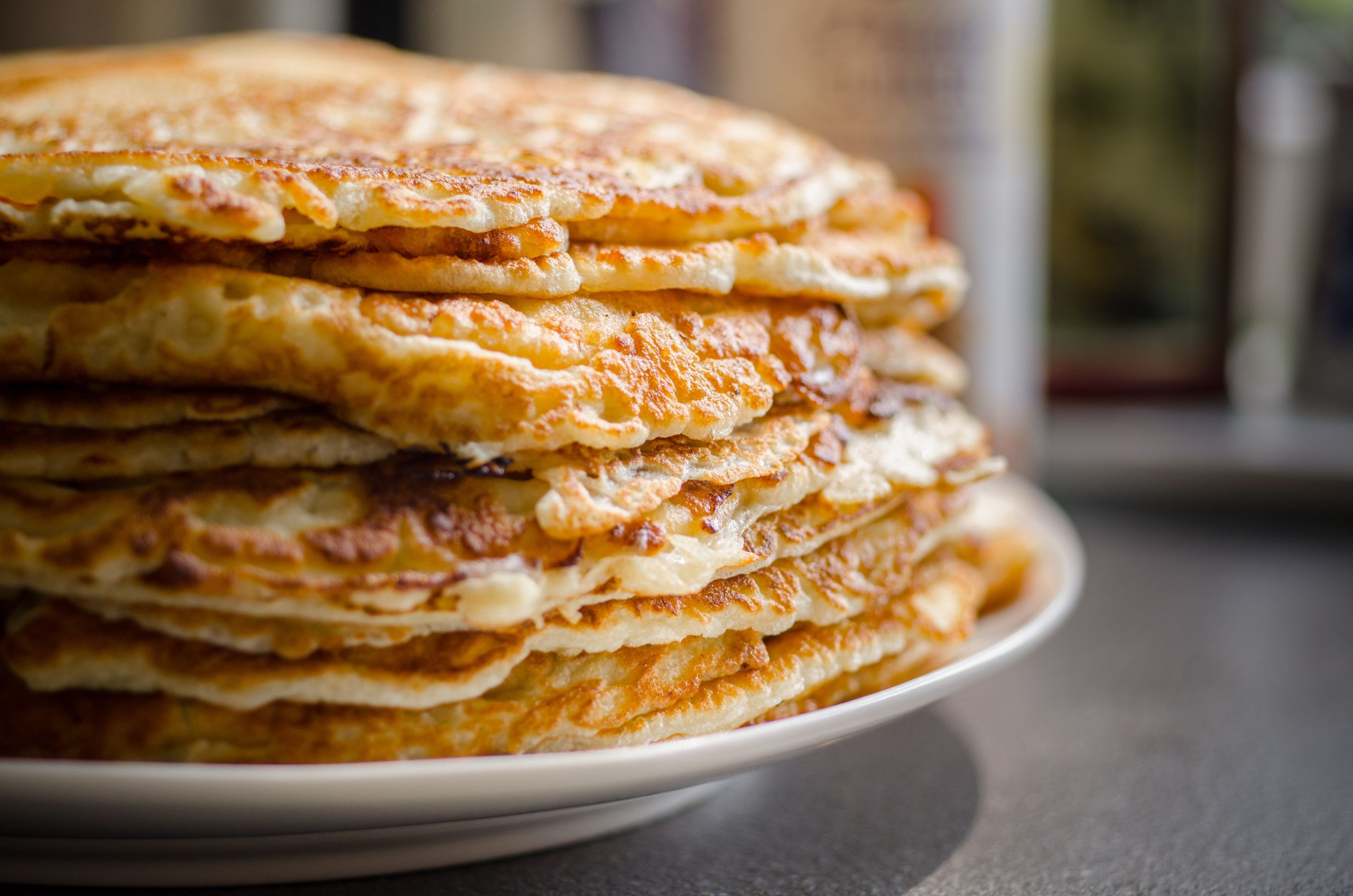 Close-up of delicious homemade pancakes stacked high on a plate, perfect for breakfast. Gros plan de délicieuses crêpes maison empilées haut sur une assiette, parfait pour le petit-déjeuner.