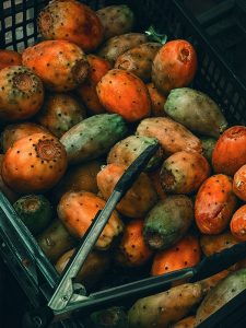 Colorful prickly pears in a crate at a Spanish market, ready for sale. Rich textures and natural hues. Des figues de Barbarie colorées dans une caisse à un marché espagnol, prêtes à être vendues. Textures riches et teintes naturelles.