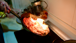 Primer plano de un filete que se está dorando con llamas en la placa de una cocina. Primer plano de un filete que se está dorando con llamas en la placa de una cocina.