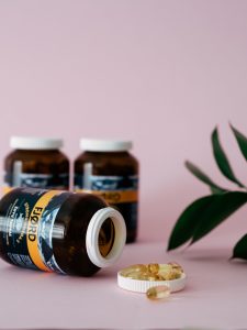 Fish oil capsules in bottles on a soft pink backdrop, perfect for health and wellness themes. Gélules d'huile de poisson dans des bouteilles sur un fond rose doux, parfait pour les thèmes de santé et de bien-être.