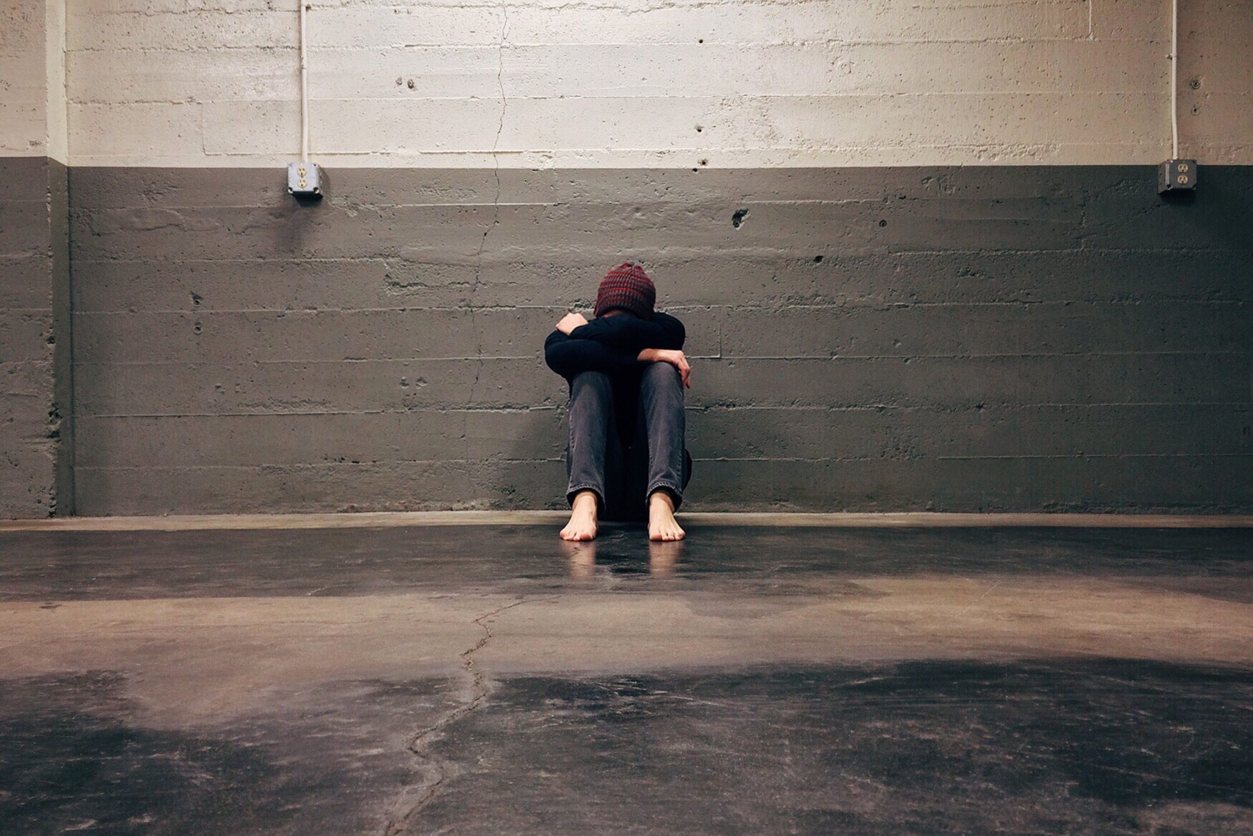 A person sitting alone in a corner, evoking themes of solitude and emotion. Une personne assise seule dans un coin, évoquant des thèmes de solitude et d'émotion.