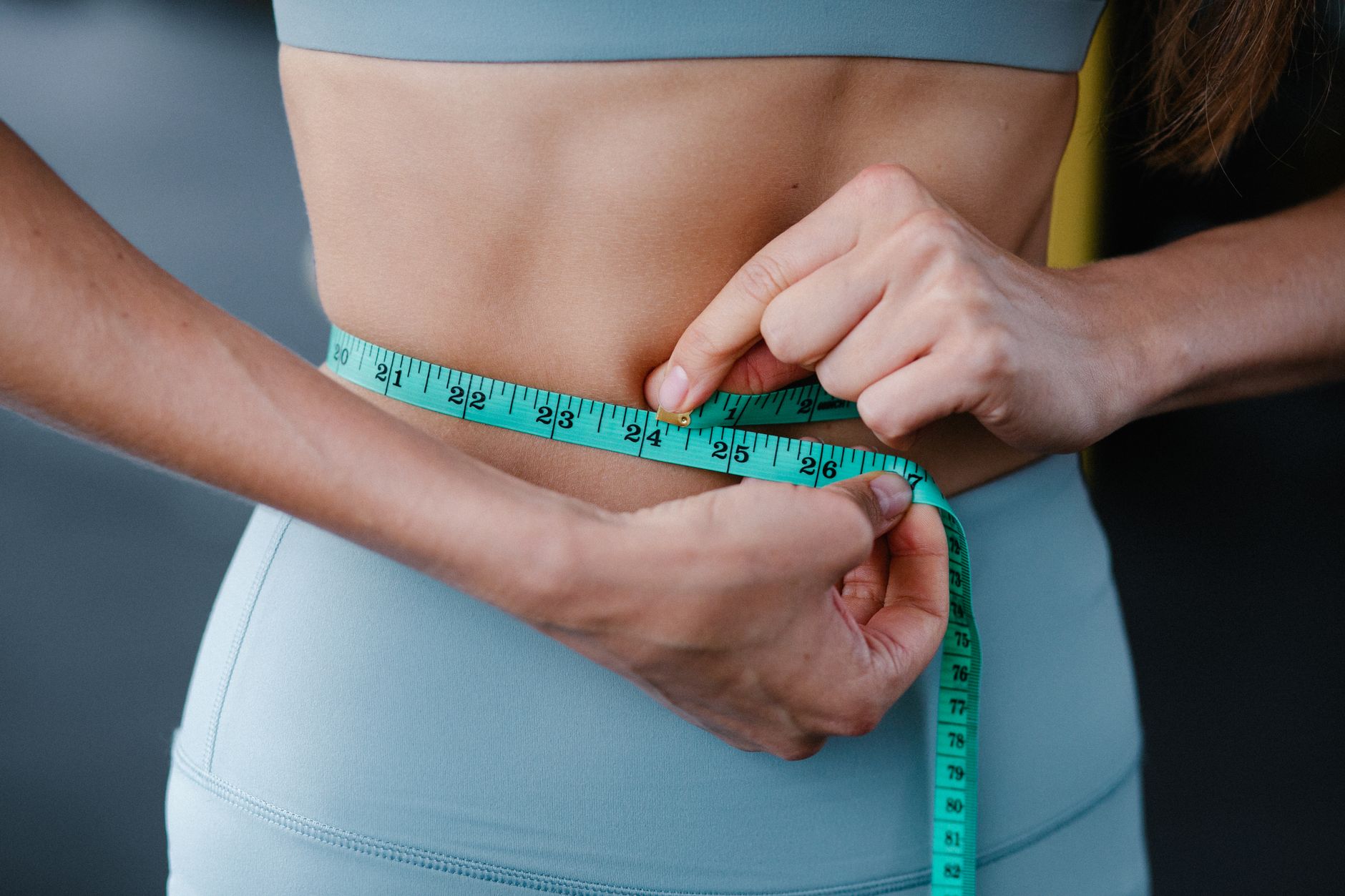 Gros plan sur une femme qui mesure son ventre avec un mètre