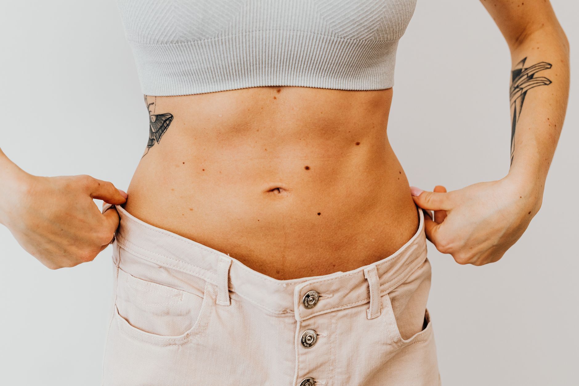 Femme qui tient son pantalon devenu trop large à la taille