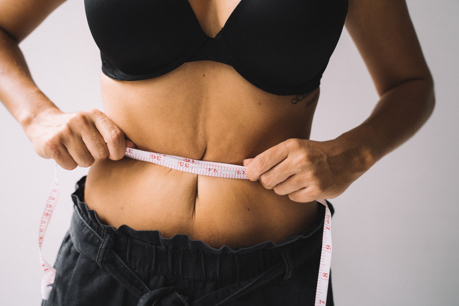 Femme qui mesure son tour de taille avec un mètre ruban