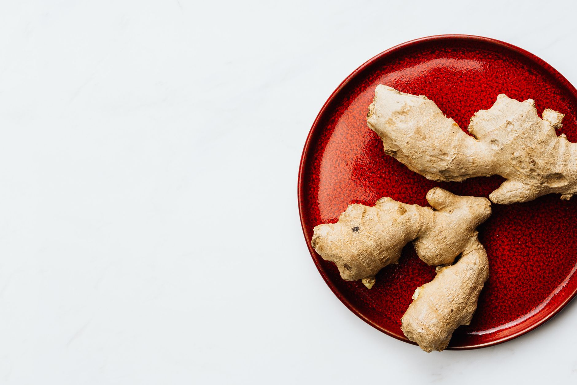 Racines de gingembre frais sur assiette rouge