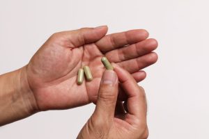 Gélules de complément alimentaire tenues dans la main