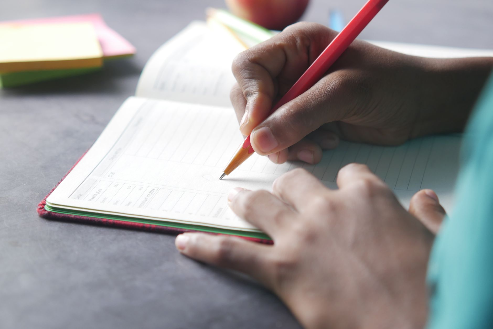Main qui note ses repas dans un carnet au crayon