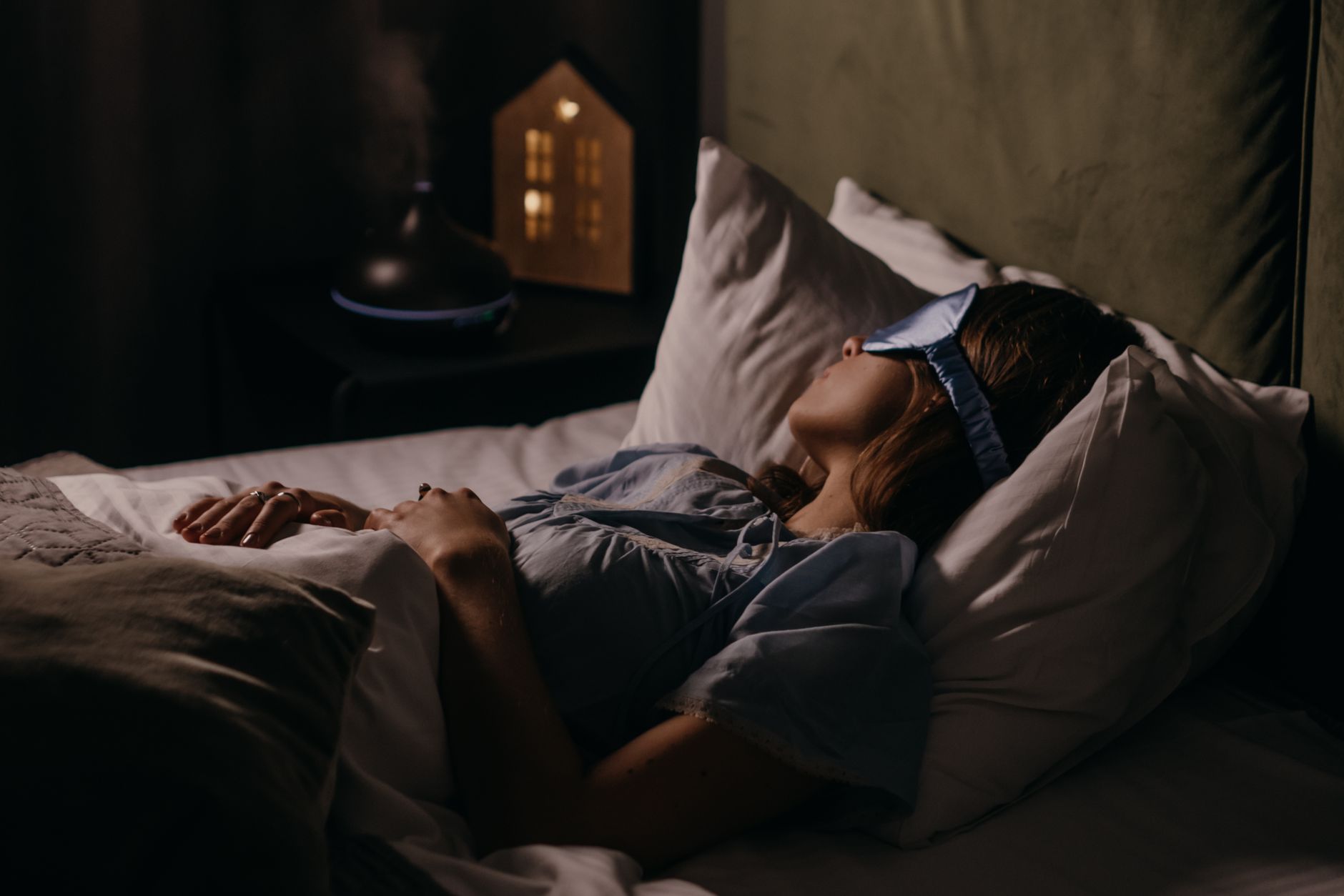 Femme endormie avec un masque de sommeil dans une chambre sombre